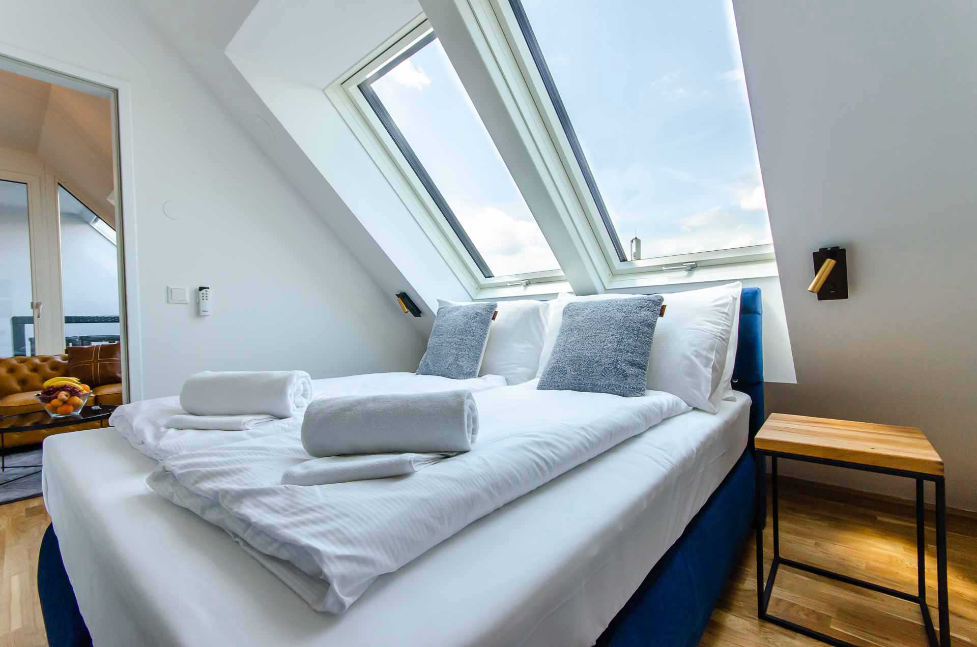 Luxurious blue bed with fresh linen and 2 big windows in